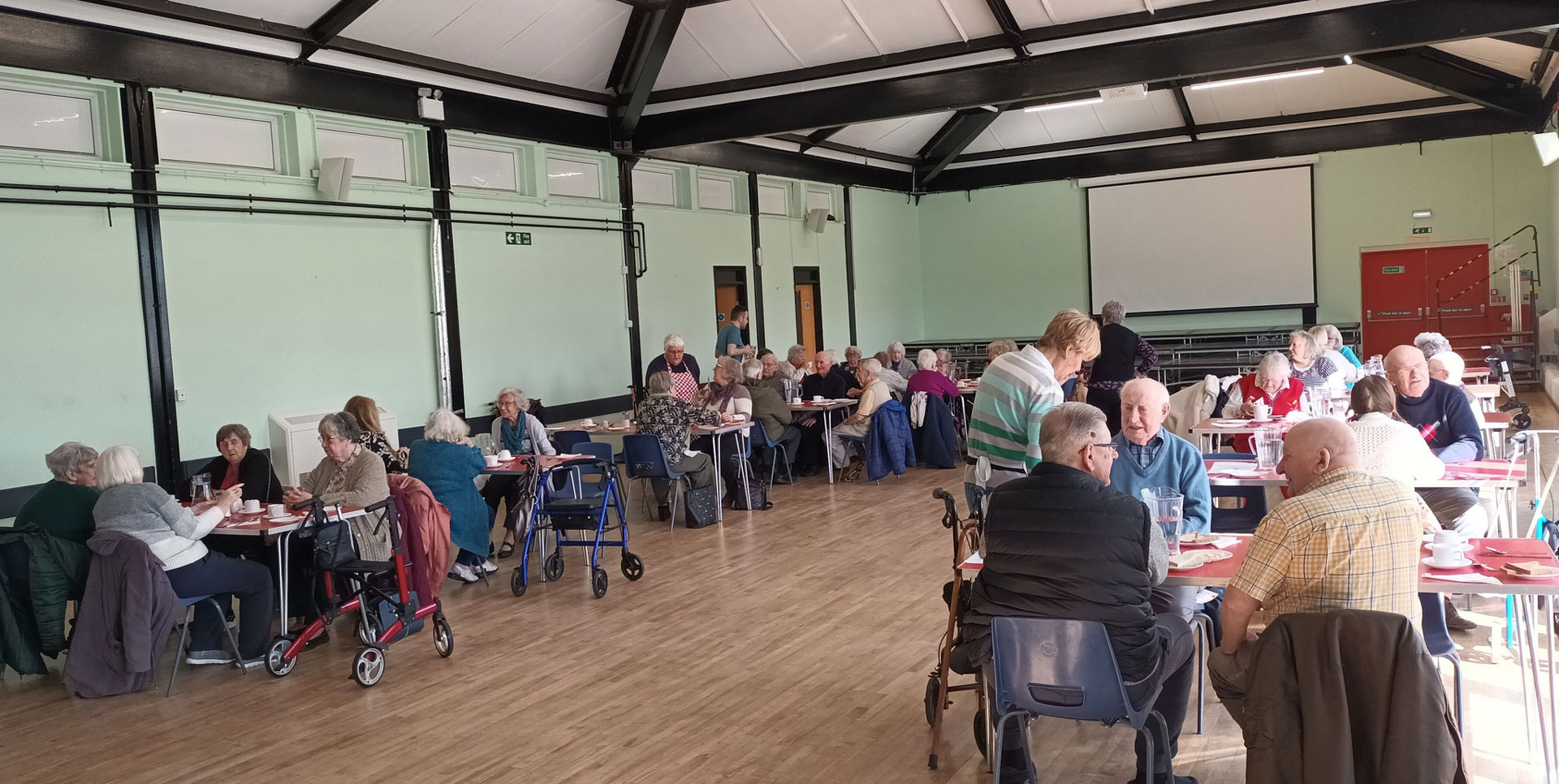 Photo of a community hall full of people enjoying a meal