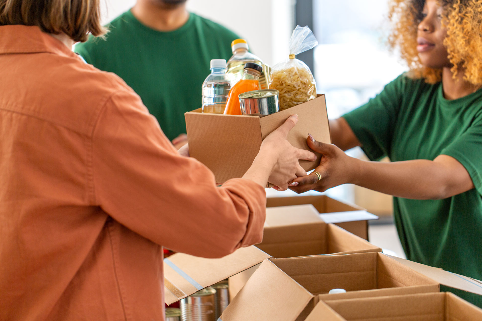 Stock image of a Foodbank volunteer handing a box of food to a customer